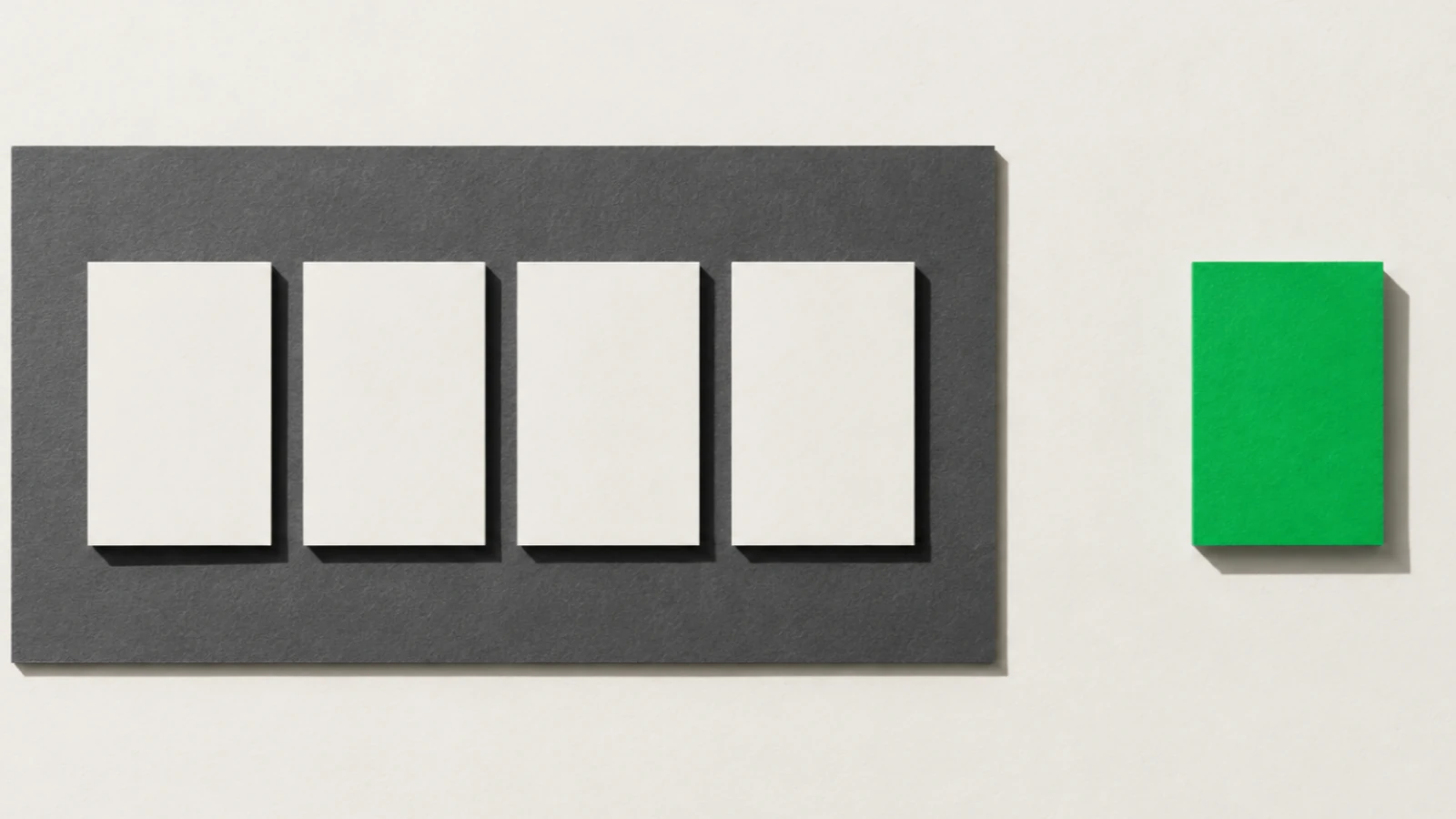 Quatre cartes de papier vierge alignées en rang serré sur une plaque de carton gris, une cinquième carte verte posée seule à l'écart sur le fond beige, ombres dures projetées vers le bas à droite.