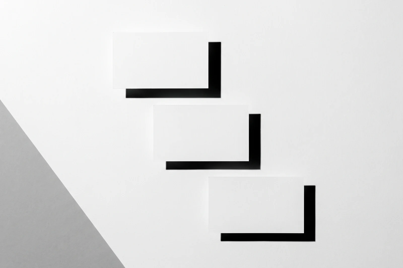 Une rangée de cartes de papier qui dérive progressivement hors de l’axe, ombres dures projetées vers le bas à droite.