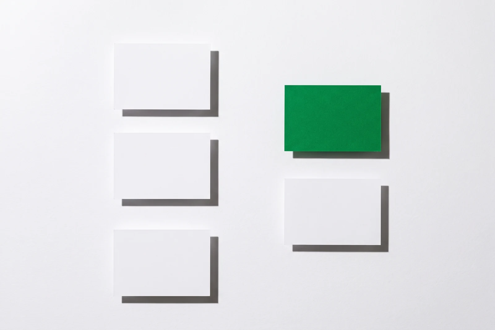 Cinq cartes disposées en deux colonnes avec des ombres portées nettes, une seule est verte.