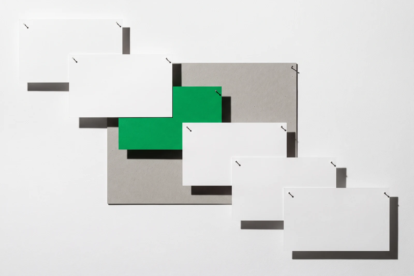 Des pièces de papier vierge disposées en escalier descendant, ombres dures projetées vers le bas à droite.