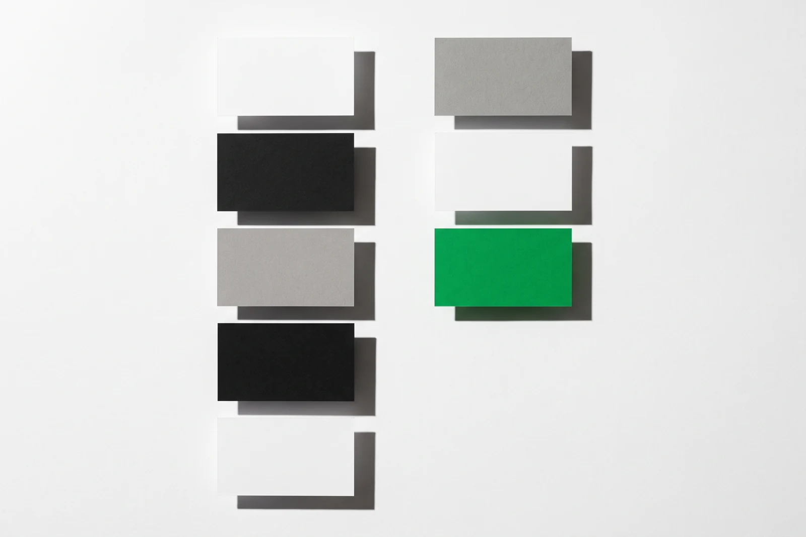 Des cartes de papier vierge triées en deux colonnes nettement séparées, ombres dures projetées vers le bas à droite.