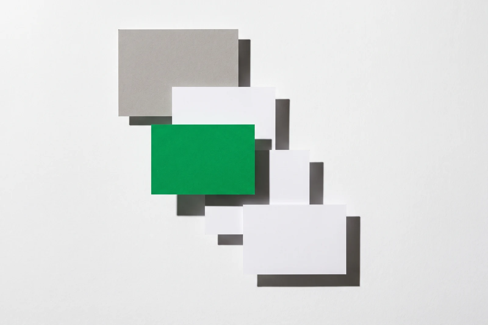 Des pièces de papier vierge disposées en escalier descendant, ombres dures projetées vers le bas à droite.