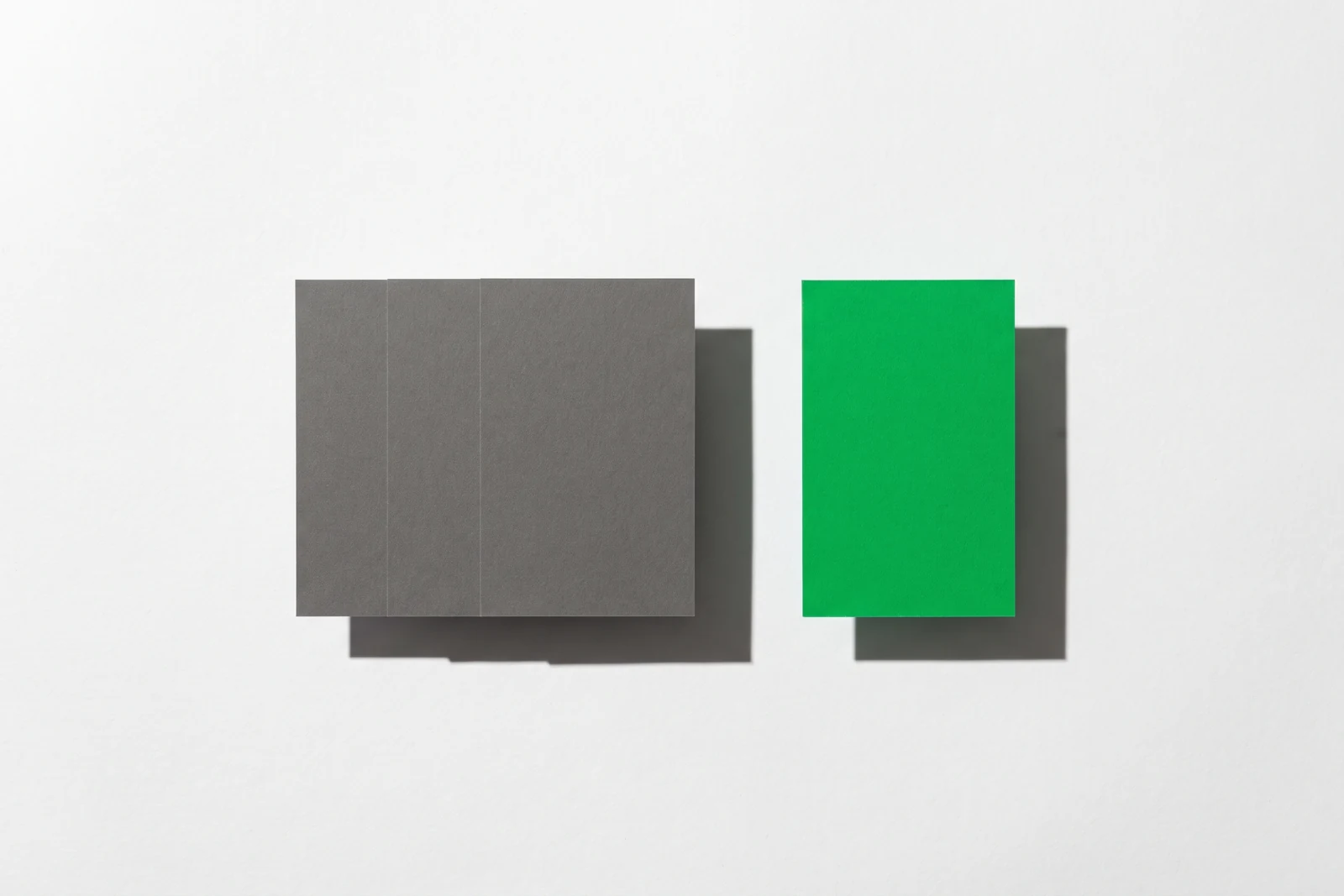 Un groupe serré de cartes de papier vierge et une carte isolée à l’écart, ombres dures projetées vers le bas à droite.