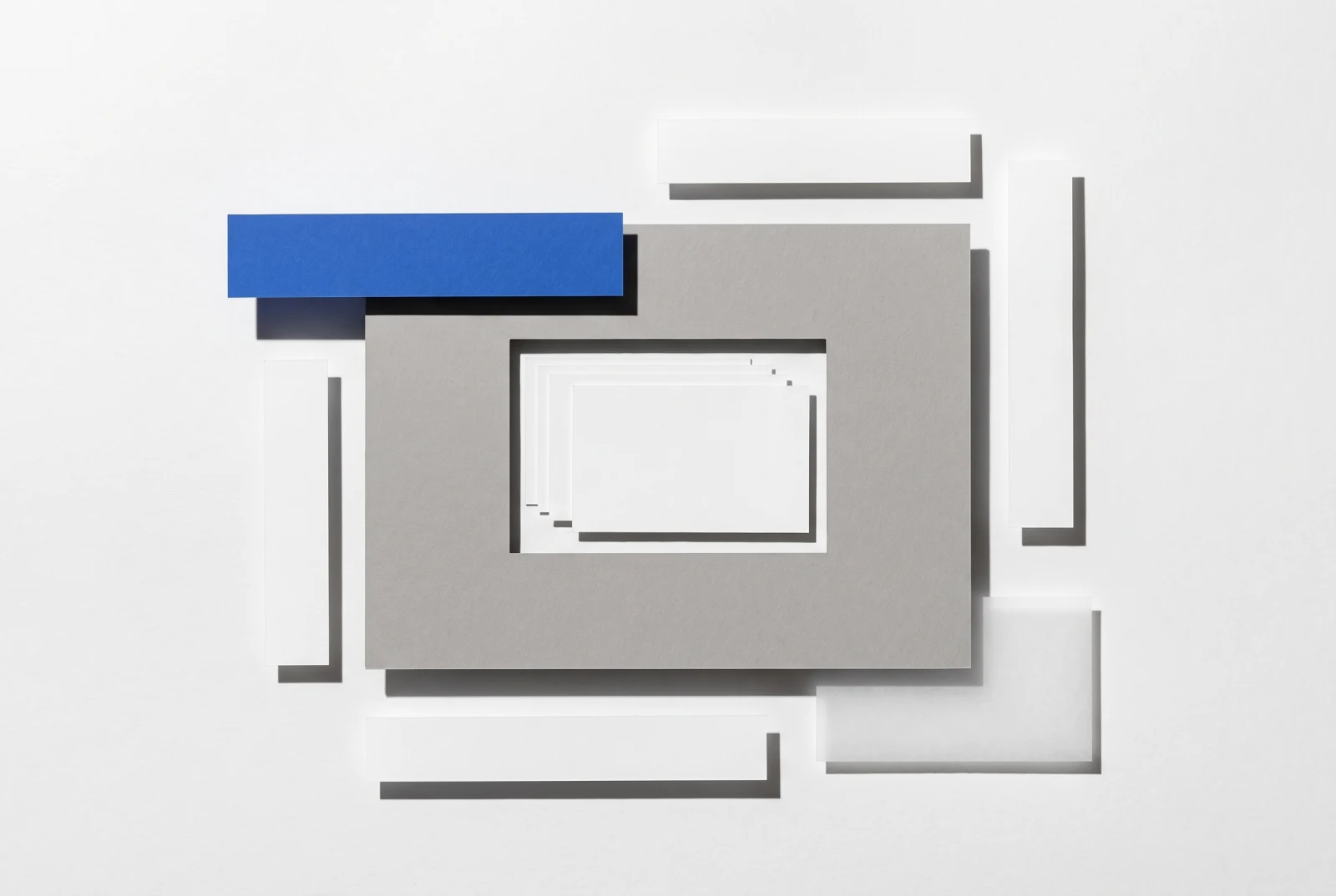 Une fenêtre rectangulaire découpée dans une plaque de carton gris laisse voir des cartes dessous, ombres dures projetées vers le bas à droite.
